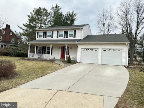 view of front of home featuring concrete driveway, a porch, a front lawn, and an attached garage