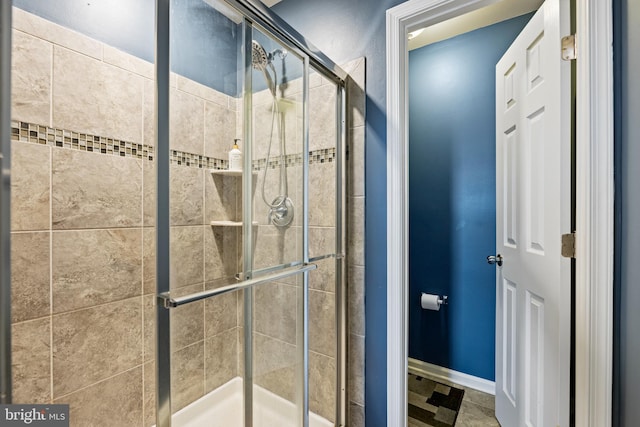 full bath featuring a shower stall and baseboards