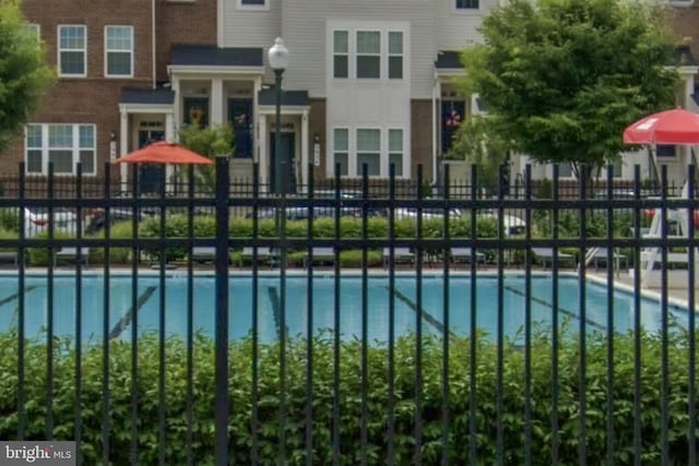 view of gate featuring fence and a community pool