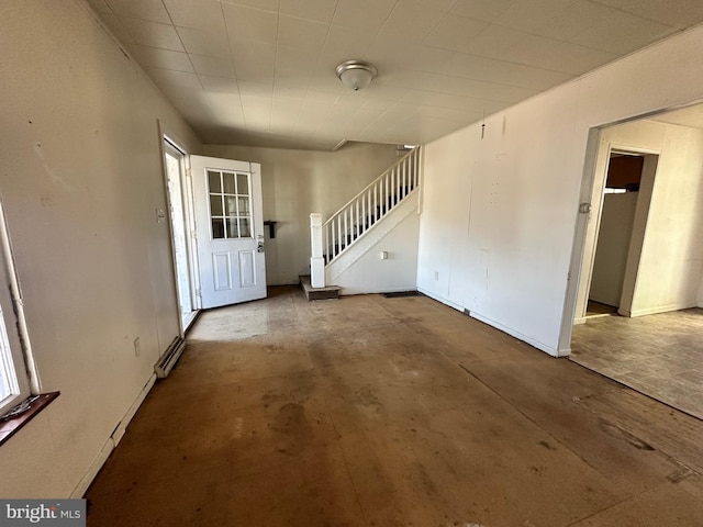 entryway with unfinished concrete flooring, baseboards, and stairs