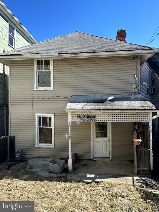 rear view of property featuring a chimney and a patio