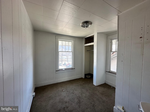 unfurnished bedroom featuring carpet floors, a closet, and wooden walls