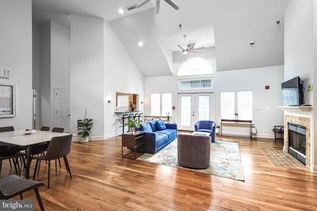 living area with french doors, visible vents, a tiled fireplace, light wood-style floors, and baseboards