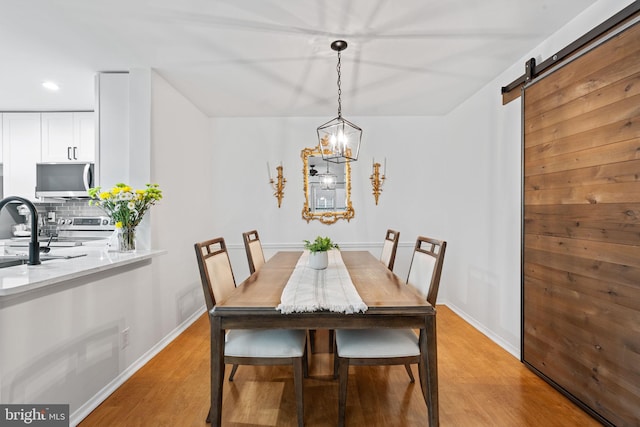 dining room featuring light wood-style floors, baseboards, and a barn door