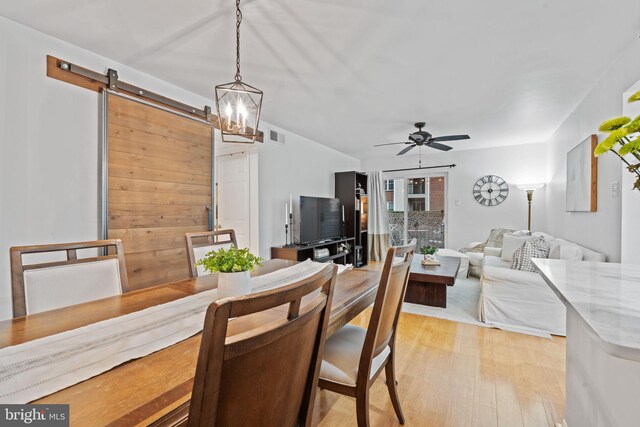 dining space with visible vents, a barn door, a ceiling fan, and light wood-style floors