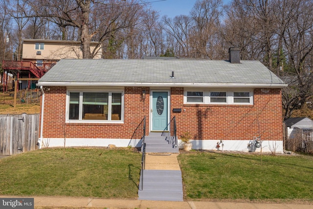 view of front facade with entry steps, a front yard, brick siding, and a chimney