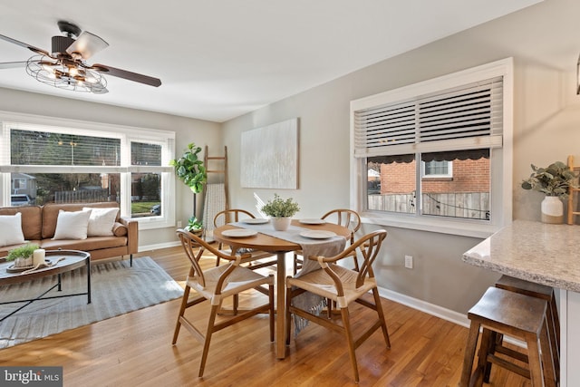 dining area with baseboards, light wood-type flooring, and ceiling fan