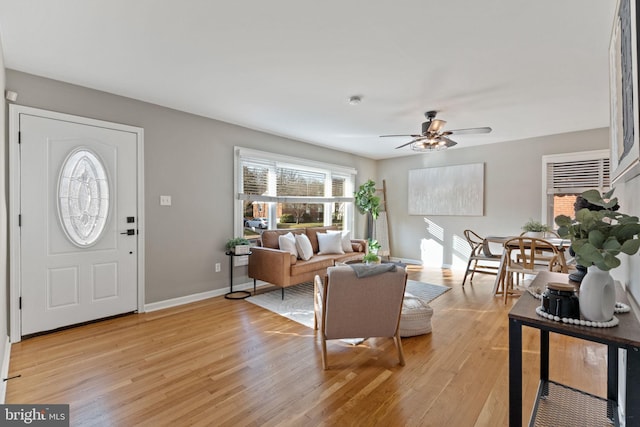 living area with ceiling fan, light wood-type flooring, and baseboards