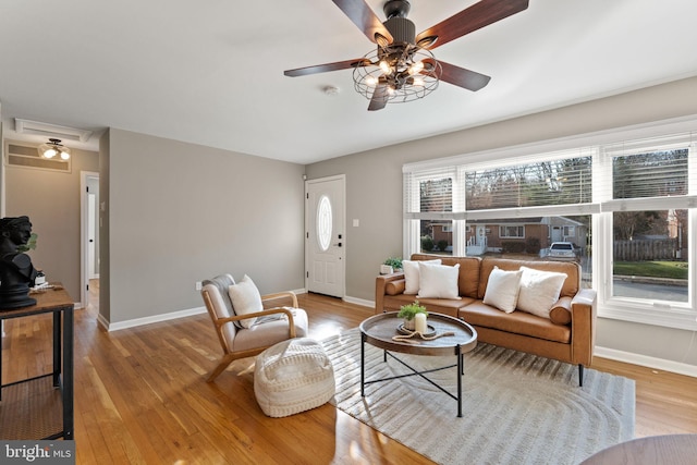 living area with a wealth of natural light, baseboards, wood finished floors, and ceiling fan