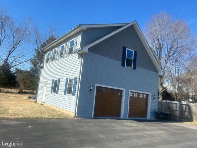 view of side of home featuring fence and an attached garage