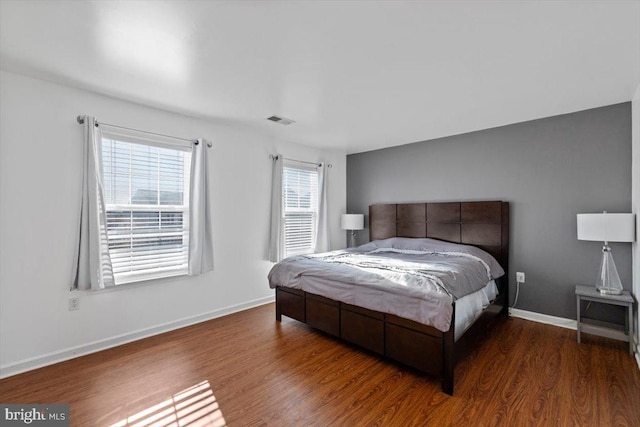 bedroom with visible vents, baseboards, and wood finished floors