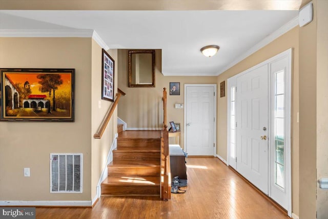 entrance foyer featuring stairs, ornamental molding, wood finished floors, and visible vents