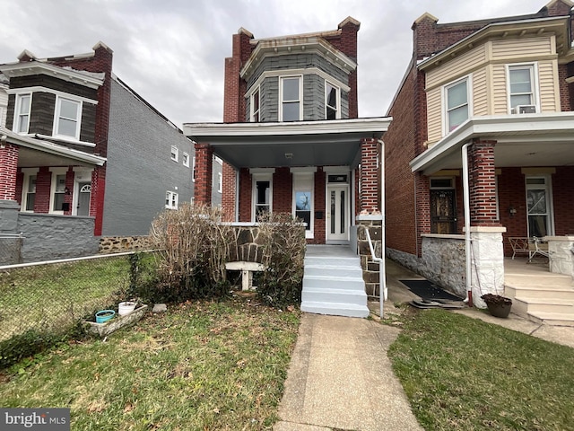 view of front facade with a porch, fence, and brick siding