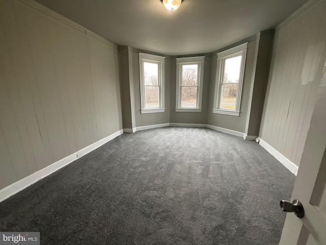 carpeted empty room featuring baseboards