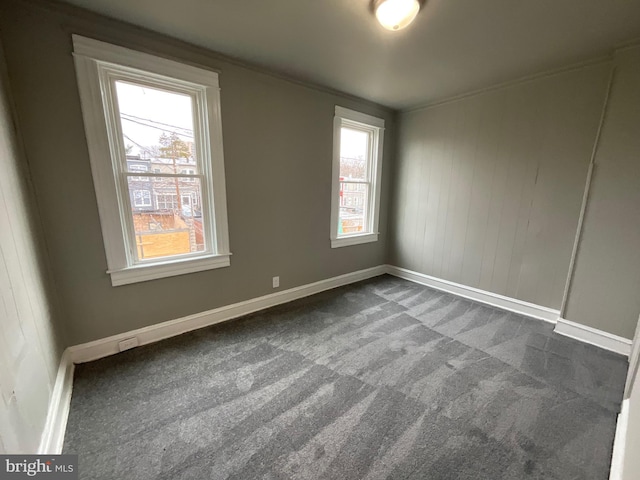 empty room featuring baseboards and dark carpet