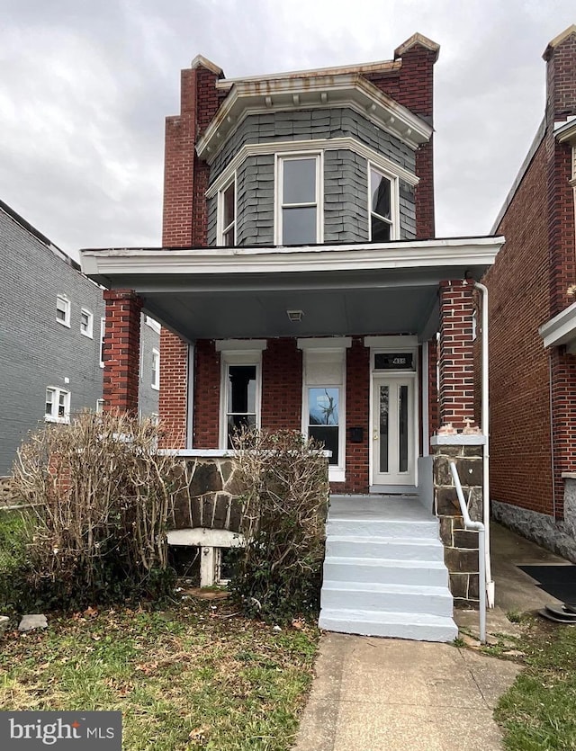 view of front facade featuring brick siding and a porch