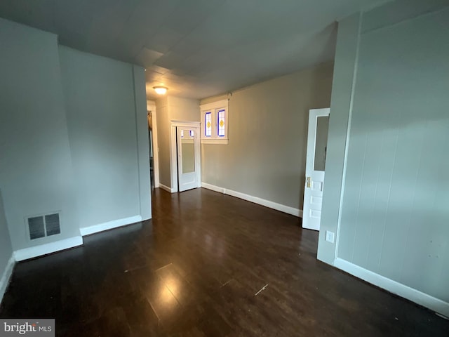 unfurnished room with visible vents, baseboards, and dark wood-style flooring