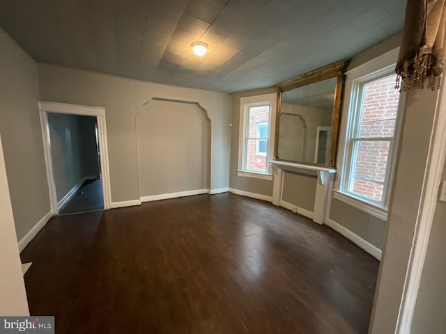 spare room with baseboards and dark wood-style flooring