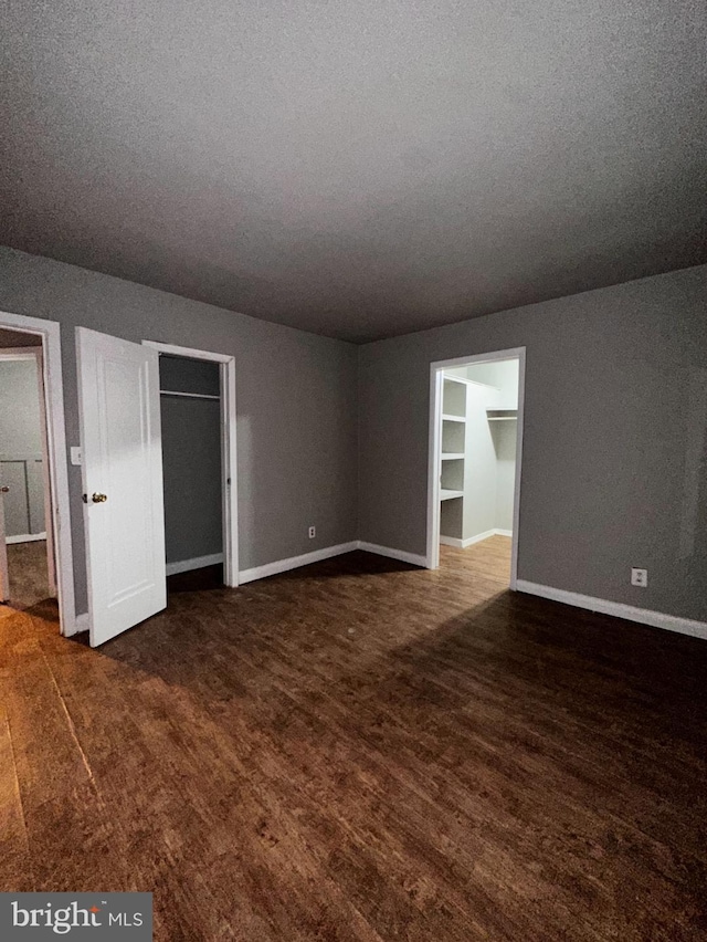 unfurnished room with a textured ceiling, baseboards, and wood finished floors