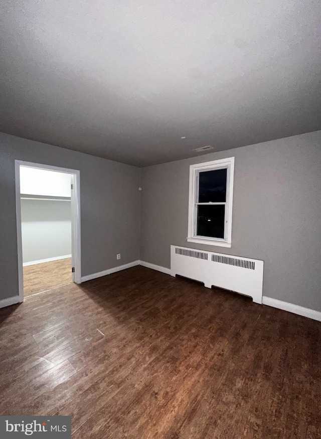 interior space with radiator heating unit, baseboards, and wood finished floors