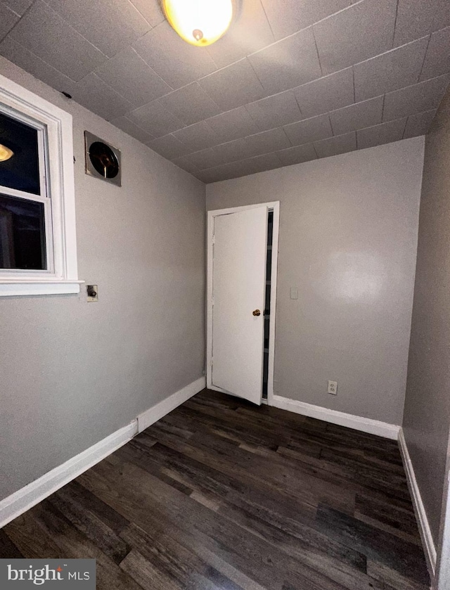 spare room featuring dark wood-style flooring and baseboards