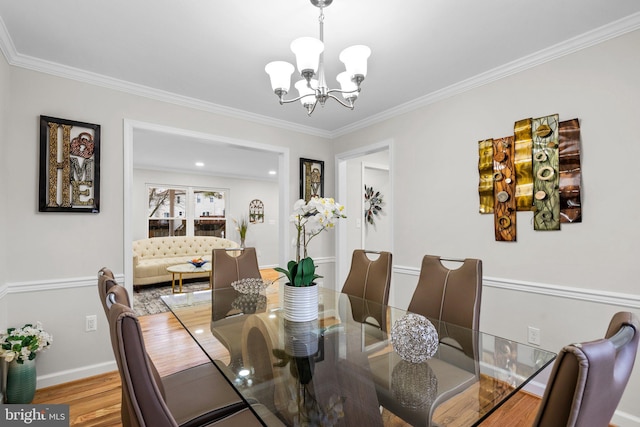 dining area with crown molding, baseboards, wood finished floors, and an inviting chandelier