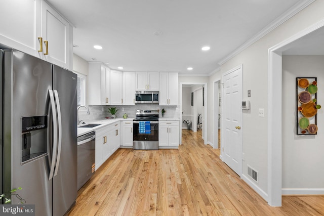 kitchen with stainless steel appliances, tasteful backsplash, visible vents, white cabinetry, and a sink