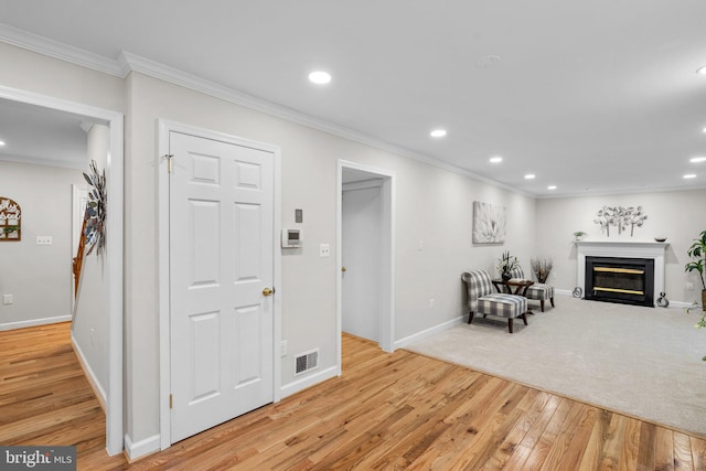 living area featuring recessed lighting, visible vents, light wood-style flooring, and ornamental molding