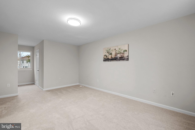 empty room featuring light carpet and baseboards