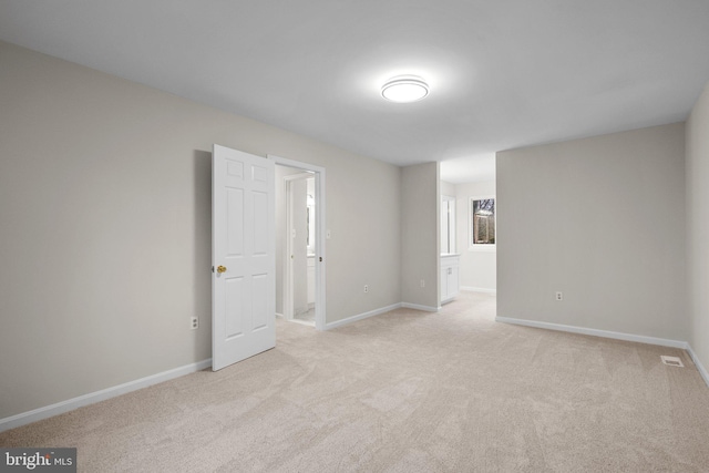 empty room with baseboards and light colored carpet