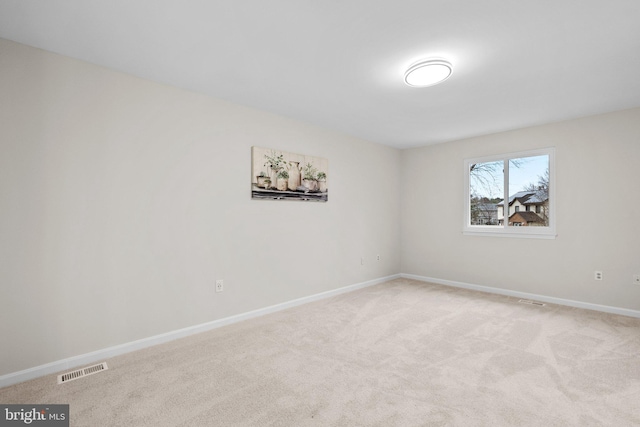 spare room with baseboards, visible vents, and light colored carpet