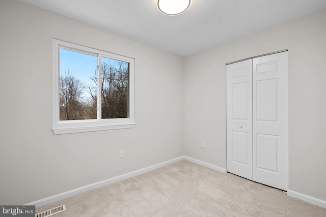 unfurnished bedroom featuring carpet, a closet, visible vents, and baseboards