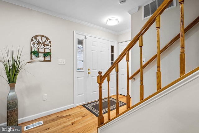 entryway featuring baseboards, wood finished floors, visible vents, and crown molding