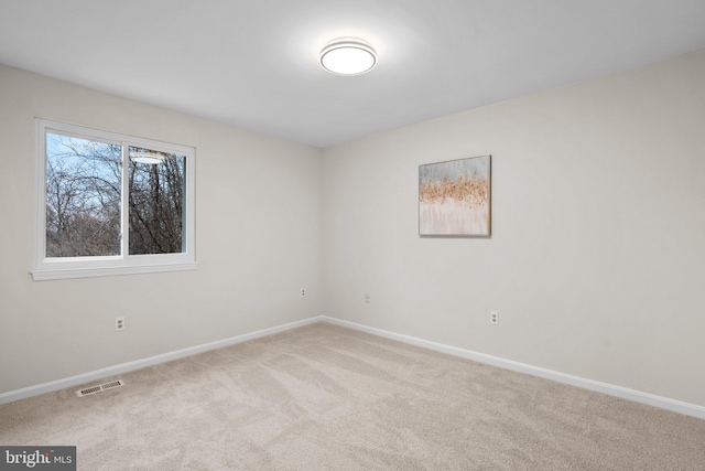 spare room featuring carpet, visible vents, and baseboards