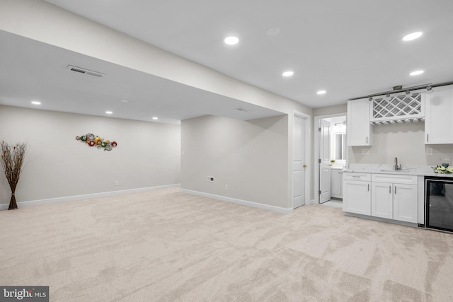 interior space with beverage cooler, a sink, white cabinets, and light colored carpet