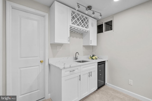 kitchen with beverage cooler, white cabinetry, a sink, and light colored carpet