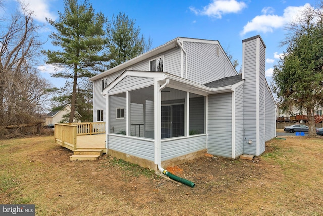 view of side of property featuring a sunroom, a chimney, a lawn, and a wooden deck