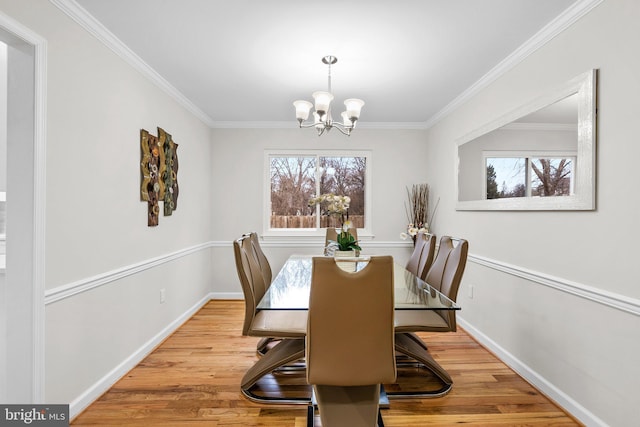 dining space featuring an inviting chandelier, baseboards, wood finished floors, and ornamental molding