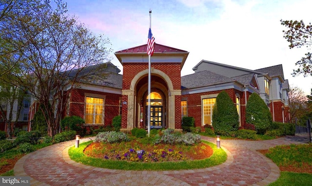 view of front of home with brick siding, french doors, and curved driveway