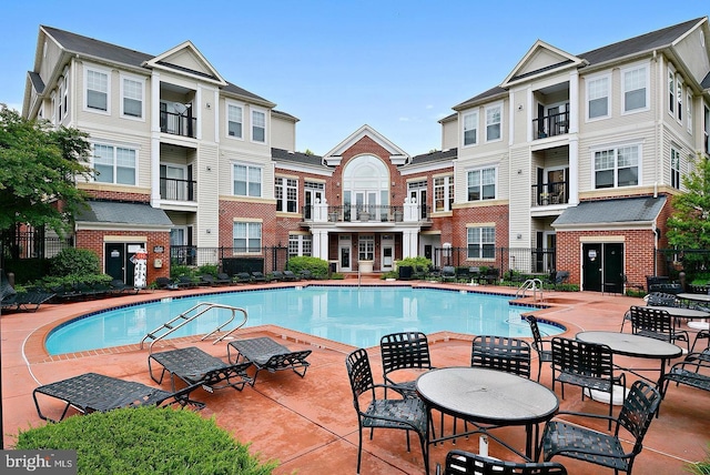 community pool featuring a patio area, fence, and a residential view