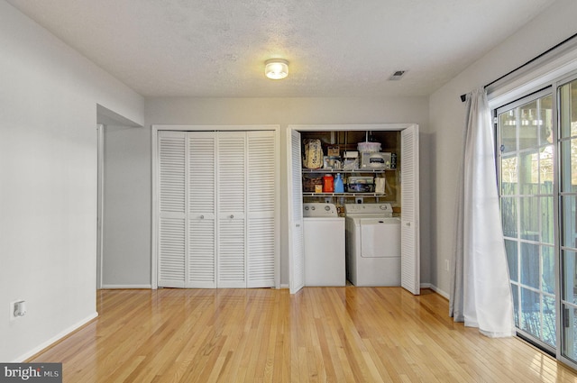 laundry area featuring a textured ceiling, washing machine and dryer, hardwood / wood-style flooring, laundry area, and baseboards