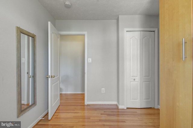 unfurnished bedroom featuring light wood-style floors, a closet, and baseboards