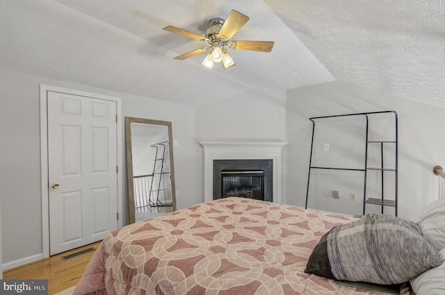 bedroom with visible vents, vaulted ceiling, a textured ceiling, and wood finished floors