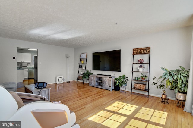 living area featuring a textured ceiling, baseboards, and wood finished floors