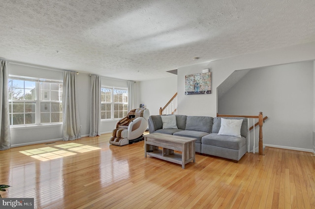 living room featuring light wood-type flooring, baseboards, and a textured ceiling