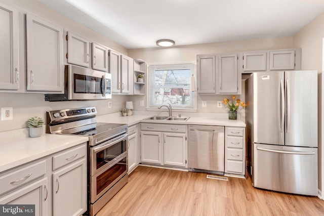 kitchen with a sink, appliances with stainless steel finishes, light countertops, and light wood finished floors