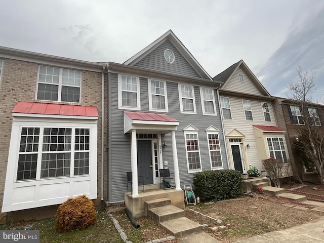 townhome / multi-family property featuring a standing seam roof, metal roof, and brick siding