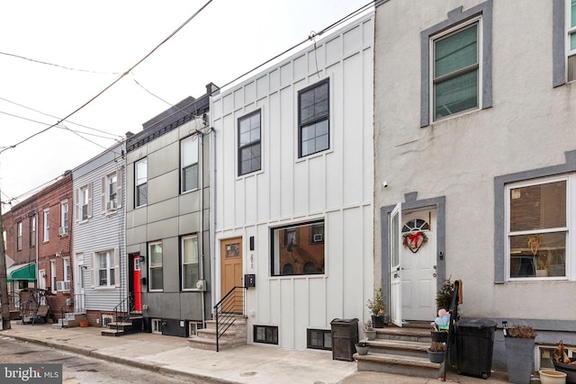 townhome / multi-family property with board and batten siding, entry steps, and stucco siding