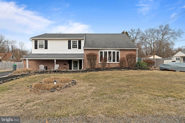 view of front facade featuring a shingled roof, a chimney, fence, a front lawn, and brick siding