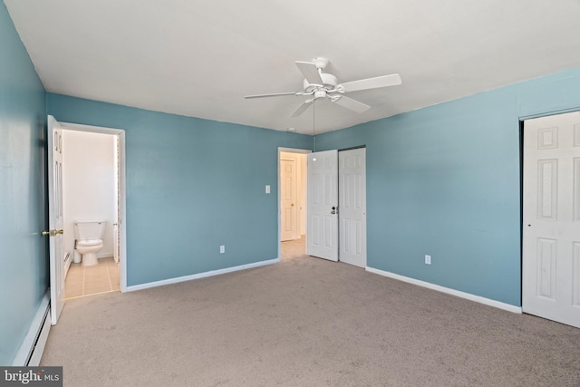 unfurnished bedroom with a baseboard heating unit, carpet flooring, baseboards, and two closets